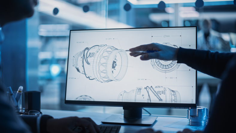 Close Up of a Desktop Computer Monitor Screen with 3D CAD Software with Prototype Jet Engine Project. Two Specialists Discussing Work, Their Hands Visible In Front of the Screen.